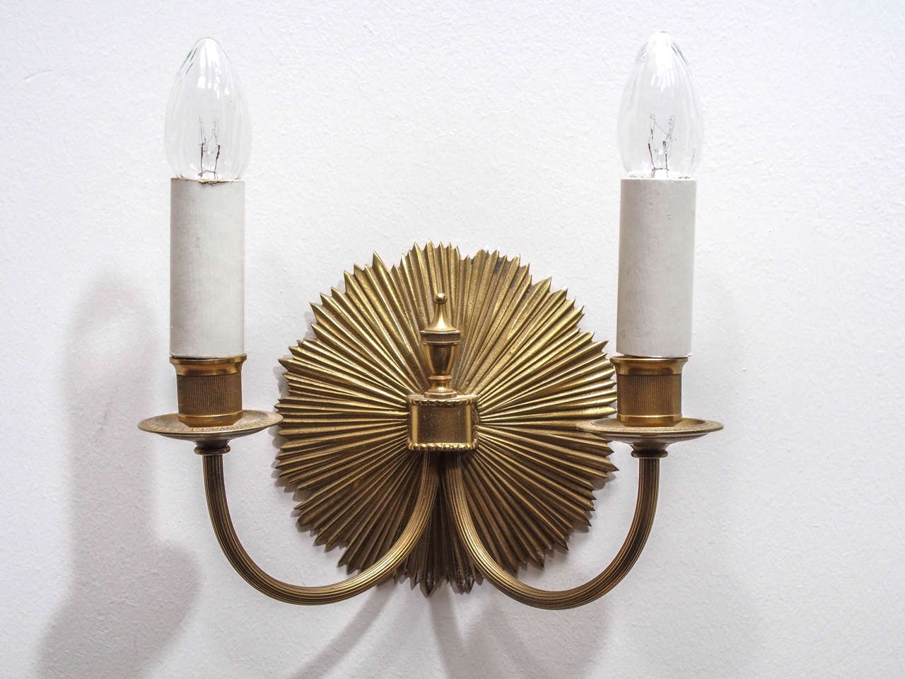 Pair of two-light gilt bronze sconces with "sunburst" backplate and urn finial at the center; height measurement below to top of socket.